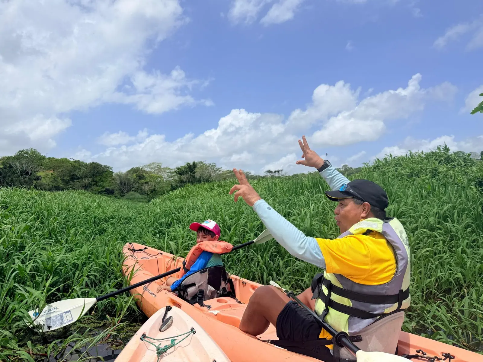 Kayak guide pointing out wildlife in a grassy channel of Gatun Lake
